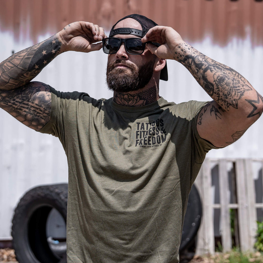 Men’s t-shirt with the words “Tattoos, fitness & freedom” #color_military-green