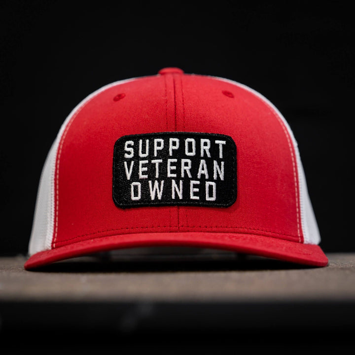 A mid-profile mesh snapback with a patch that says “Support veteran owned” in white letters #color_red-white