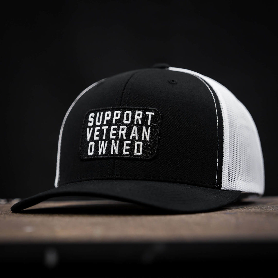 A black mid-profile mesh snapback with a patch that says “Support veteran owned” in white letters #color_black-white