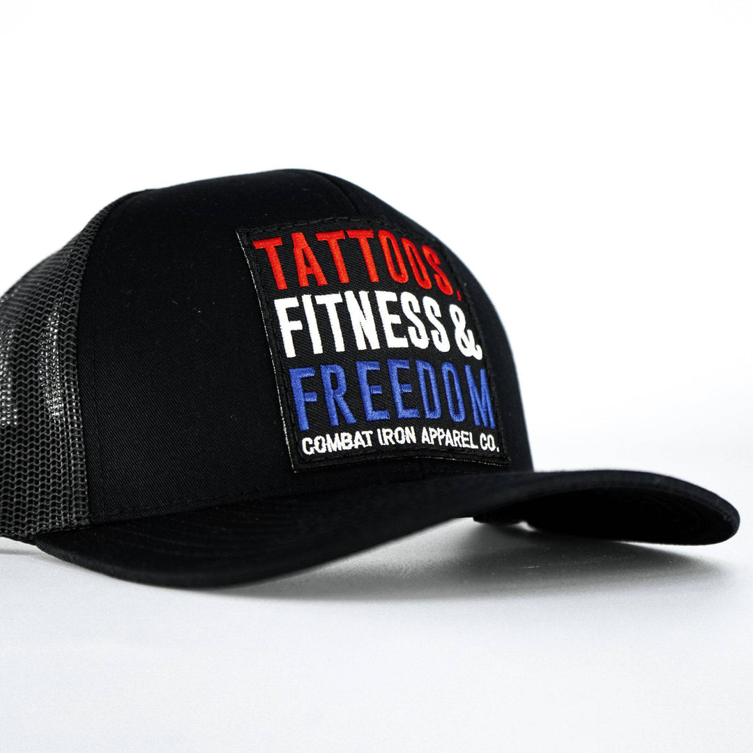 A black mid-profile mesh snapback with a print that says “Tattoos, fitness & freedom” #color_black-black