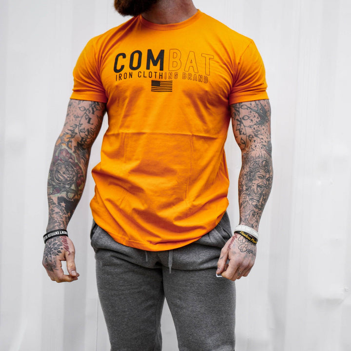Men’s orange t-shirt with the words “Combat Iron clothing brand” on the front and an American flag #color_orange