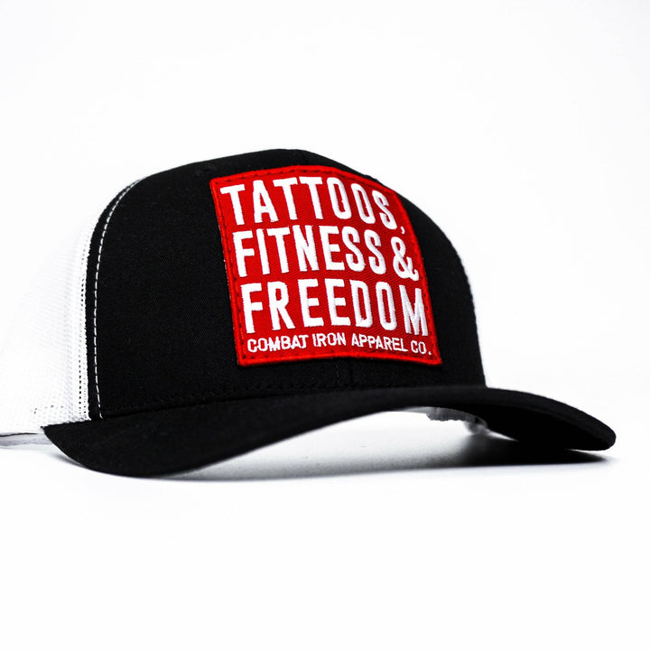 A black mid-profile mesh snapback with a red patch saying “Tattoos, fitness & freedom” in white letters #color_black-white