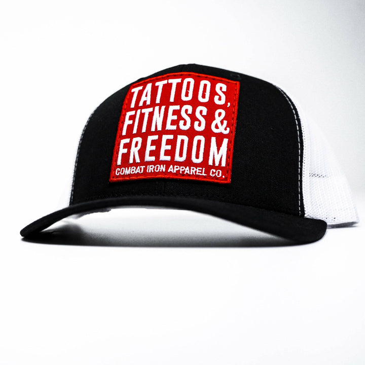 A black mid-profile mesh snapback with a red patch saying “Tattoos, fitness & freedom” in white letters #color_black-white
